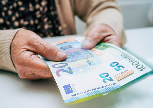 Ältere Person hält Euro-Geldscheine in der Hand