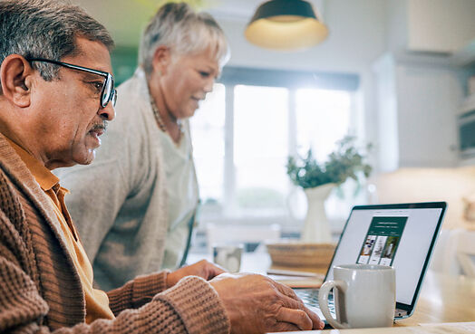 Seniorenpaar am Laptop in der Küche Älteres Paar sitzt gemeinsam am Laptop